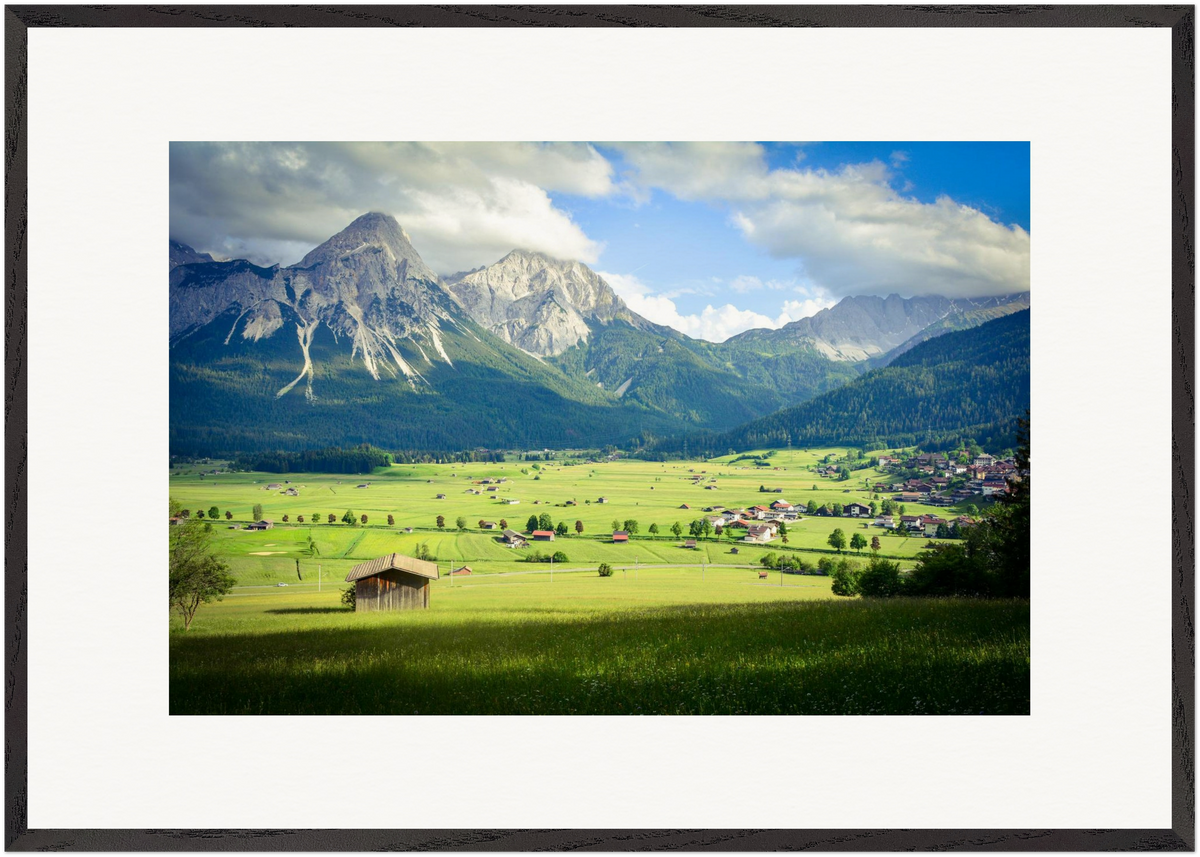 „Das Tal der Einhörner“ – horizontale Fine-Art-Fotografie von Stanislav Shnaider. Eine weite grüne Landschaft mit traditionellen Häusern und mächtigen Bergen im Hintergrund. Limitierte Fotokunst im Format 70 × 100 cm.