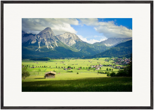 „Das Tal der Einhörner“ – horizontale Fine-Art-Fotografie von Stanislav Shnaider. Eine weite grüne Landschaft mit traditionellen Häusern und mächtigen Bergen im Hintergrund. Limitierte Fotokunst im Format 70 × 100 cm.