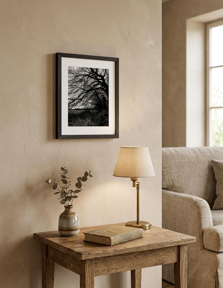 Gerahmte Schwarz-Weiß-Fotografie eines Baumes in einem hellen Wohninterieur mit natürlichen Holzmöbeln und warmen Beigetönen.