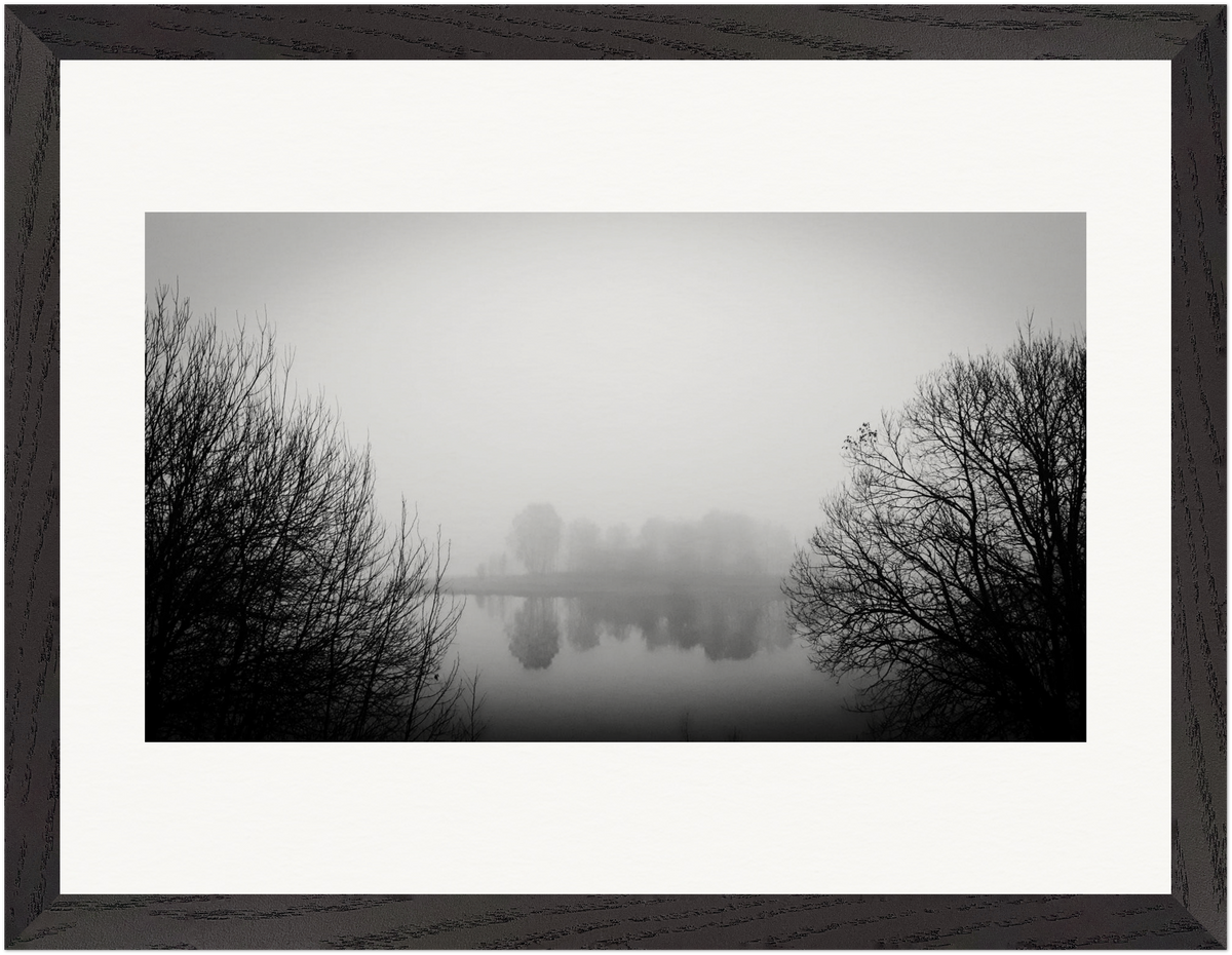 Gerahmte Schwarz-Weiß-Fotografie einer nebligen Landschaft mit Bäumen und Spiegelung im Wasser.